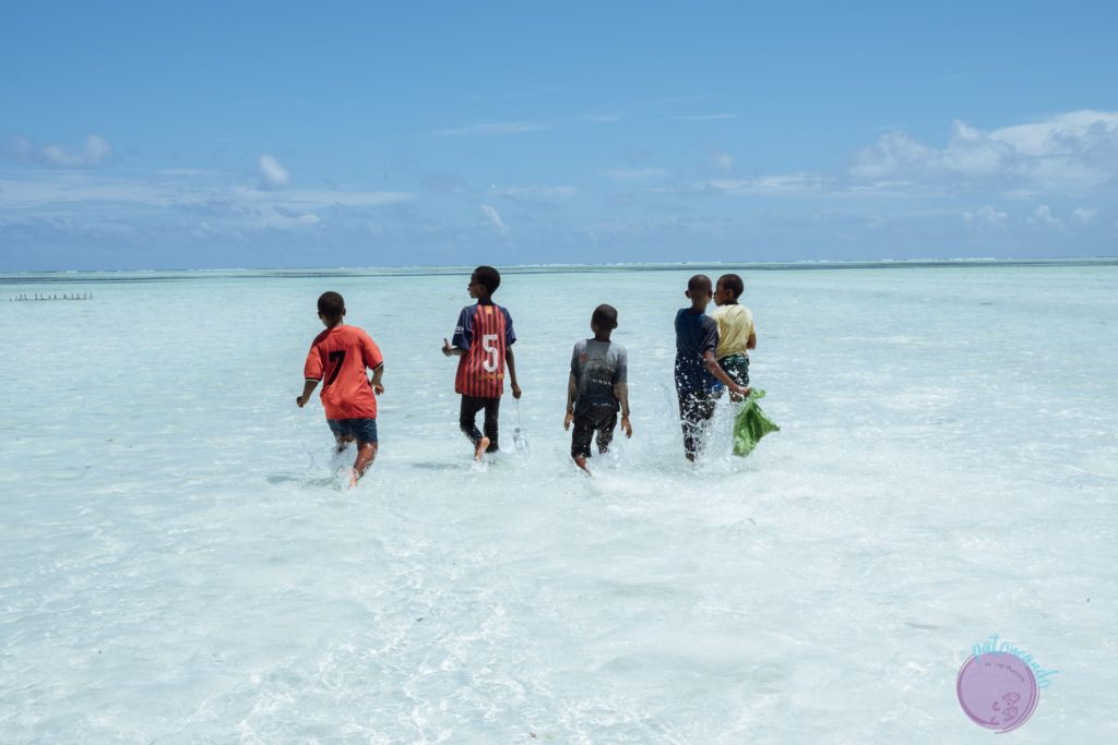 Consejos para viajar a Zanzibar - niños jugando en el agua en playa- Patoneando blog de viajes